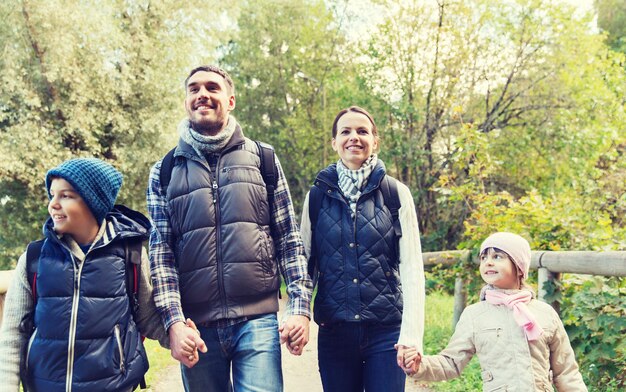 concept d'aventure, de voyage, de tourisme, de randonnée et de personnes - famille heureuse marchant avec des sacs à dos dans les bois