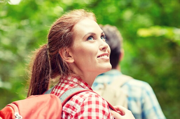 concept d'aventure, de voyage, de tourisme, de randonnée et de personnes - groupe d'amis souriants marchant avec des sacs à dos dans les bois