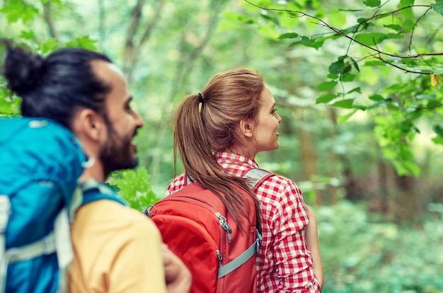 Photo concept d'aventure, de voyage, de tourisme, de randonnée et de personnes - groupe d'amis souriants marchant avec des sacs à dos dans les bois