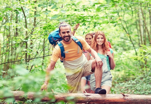 concept d'aventure, de voyage, de tourisme, de randonnée et de personnes - groupe d'amis souriants marchant avec des sacs à dos dans les bois