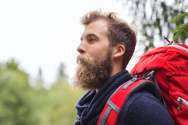 concept d'aventure, de voyage, de tourisme, de randonnée et de personnes - homme souriant avec barbe et sac à dos rouge randonnée