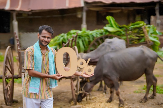 Concept bancaire ou financier : Jeune agriculteur indien montrant le symbole zéro pour cent dans sa ferme d'élevage