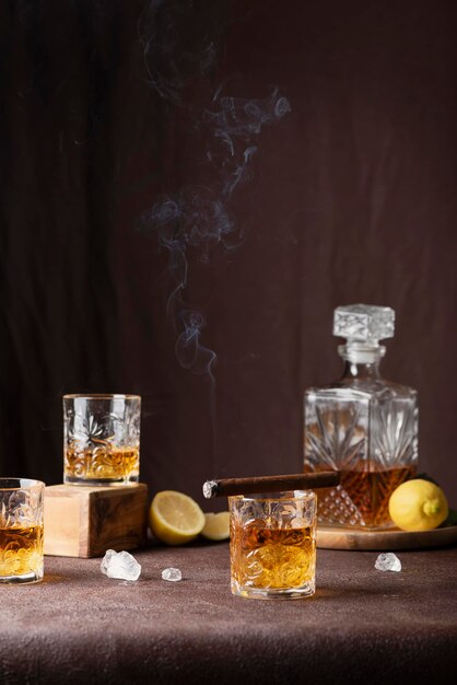 Concept de bar : verres de rhum avec glace, citron et cigare sur fond marron, image de mise au point sélective