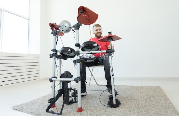 Concept de batteur, de tambour, de musique et de personnes - batteur de jeune homme jouant dans la salle blanche.