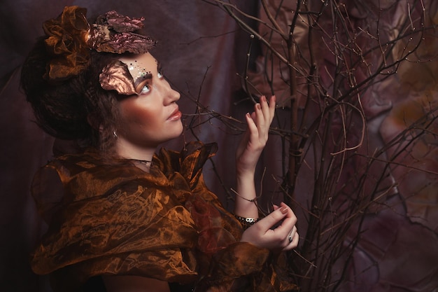 Concept de beauté et d'art Jeune femme avec un maquillage lumineux avec des branches sèches