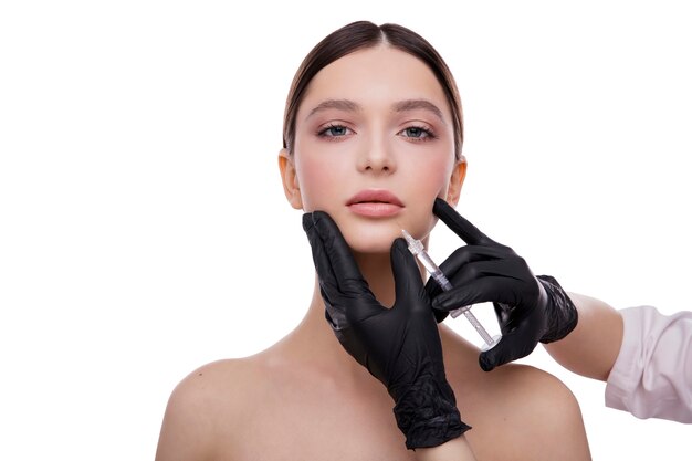 Concept de beauté de cosmétologie visage et main de belle jeune femme avec l'injection de fabrication de seringue