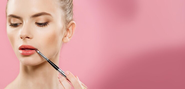 Concept de beauté Femme appliquant du rouge à lèvres rouge avec fond de studio rose Belle fille fait du maquillage