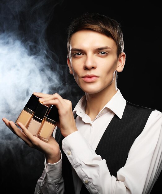 Concept de beauté Jeune maquilleur masculin posant avec fond de teint pour le maquillage
