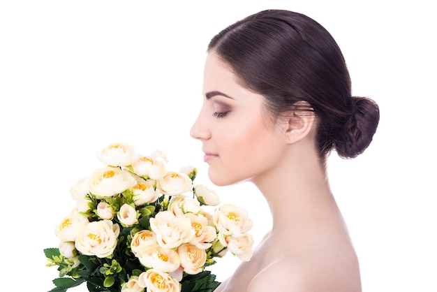 Concept de beauté naturelle - vue latérale d'une belle jeune femme avec des fleurs isolées sur fond blanc