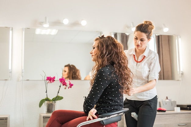 Concept de beauté et de personnes heureuse jeune femme avec un coiffeur au salon de coiffure