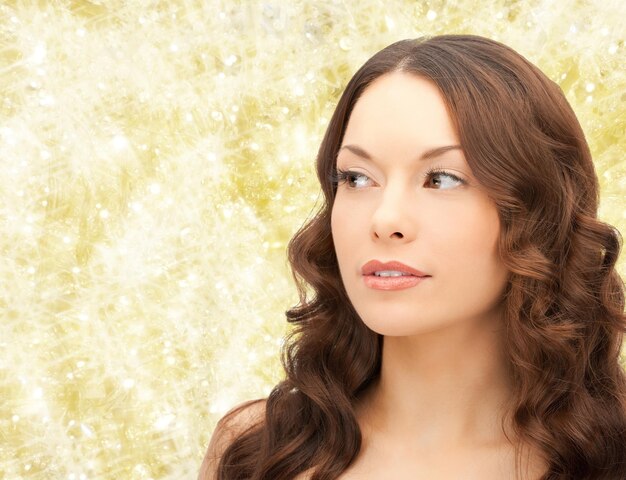 concept de beauté, de personnes et de santé - beau visage de jeune femme sur fond de feux jaunes