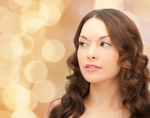 concept de beauté, de personnes et de santé - beau visage de jeune femme sur fond de lumières beiges