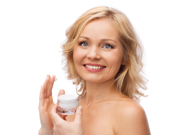 concept de beauté, de personnes, de soins de la peau et de cosmétiques - femme heureuse appliquant de la crème sur son visage