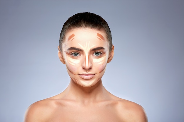 Concept de beauté. Portrait de femme avec contouring sur le visage, base pour le maquillage. Types de dessin de maquillage, tête et épaules de fille avec maquillage nu regardant la caméra