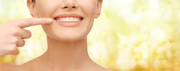 concept de beauté et de santé dentaire - photo en gros plan d'une belle femme pointant le doigt vers ses dents