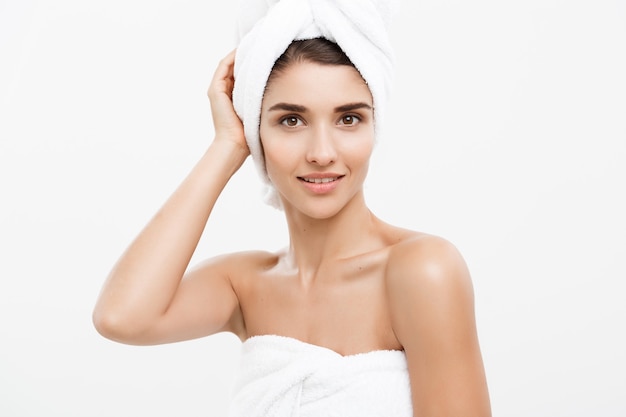 Concept de beauté et de soins de la peau - belle jeune femme caucasienne avec une serviette de bain sur la tête couvrant ses seins, sur blanc.