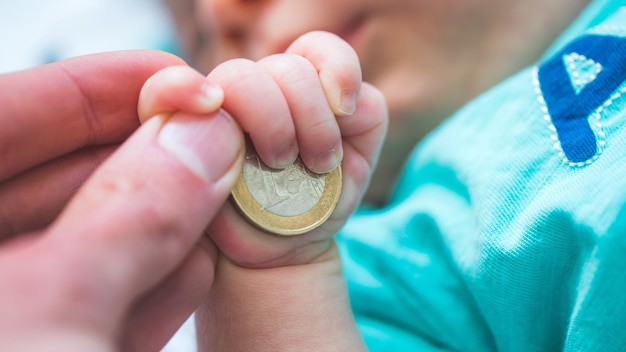 Concept de bébé d'assurance vieillesse Gros plan sur un nouveau-né tenant une pièce de monnaie