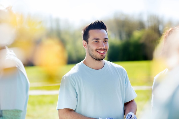 concept de bénévolat, de charité, de personnes, de travail d'équipe et d'environnement - homme bénévole heureux dans le parc