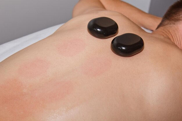 Photo concept de bien-être un beau jeune homme se détend sous l'effet stimulant d'un massage traditionnel aux pierres chaudes dans un spa de luxe et un centre de bien-être récupération après le travail