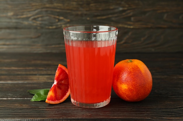 Concept de boire du jus d'orange rouge sur une table en bois