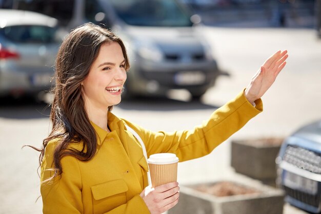 concept de boissons et de personnes - heureuse jeune femme ou adolescente buvant du café à partir d'une tasse de papier dans la rue de la ville