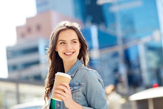 concept de boissons et de personnes - heureuse jeune femme ou adolescente buvant du café à partir d'une tasse de papier dans la rue de la ville