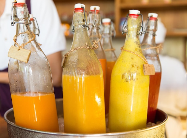 concept de boissons, de soif, de rafraîchissement et de vente - bouteilles de jus de fruits ou de légumes dans un seau à glace au marché