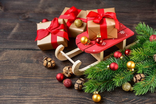 concept de boîtes-cadeaux festives de Noël ou du nouvel an. décoration de cadeau arcs rouges branche d'arbre de Noël et boules brillantes