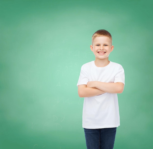 concept de bonheur, d'enfance, d'éducation, d'école et de personnes - petit garçon souriant en t-shirt blanc sur fond de tableau vert