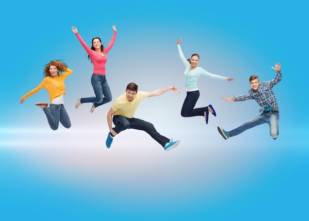 concept de bonheur, de liberté, d'amitié, de mouvement et de personnes - groupe d'adolescents souriants sautant dans l'air sur fond laser bleu
