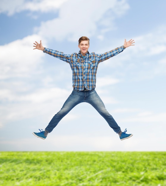 concept de bonheur, de liberté, de vacances, d'été et de personnes - jeune homme souriant sautant dans l'air sur fond naturel