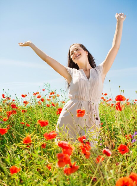 concept de bonheur, de nature, d'été, de vacances et de personnes - jeune femme souriante sur un champ de pavot