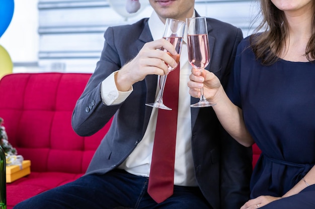 Concept de bonne année 2022, couple heureux tenant des verres de champagne tintant à la fête de Noël et du nouvel an après avoir terminé le travail commercial