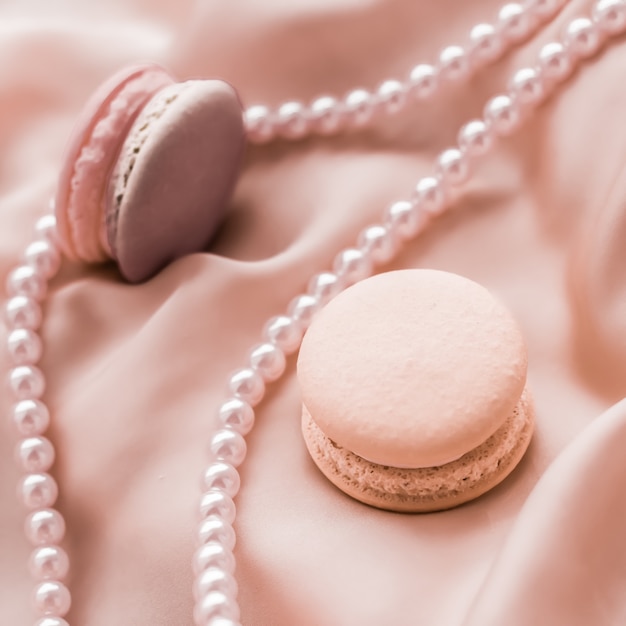 Concept de boulangerie et de marque Girly macarons sucrés et bijoux de perles sur fond de soie bijoux chic parisien dessert français nourriture et gâteau macaron pour cadeau de vacances de marque de confiserie de luxe