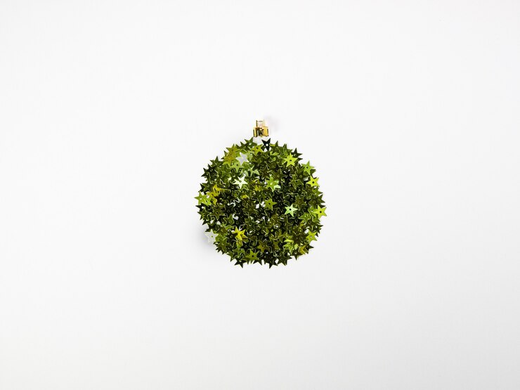 Photo concept de boules créatives fait avec des confettis d'étoiles vertes brillantes avec ruban rouge sur le dessus sur la vue de dessus de décoration de noël à plat blanc