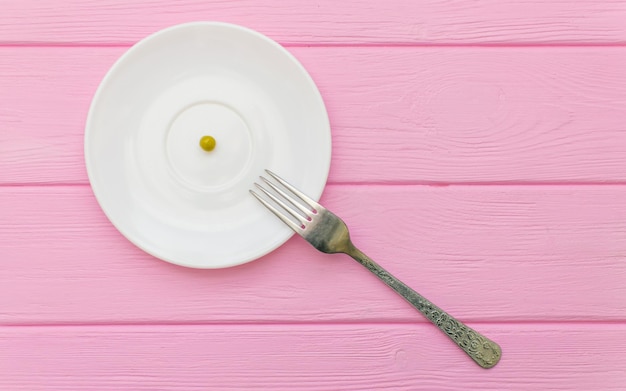 Le concept de boulimie de famine Pois sur une assiette blanche et une fourchette