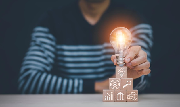 Photo concept brainstorming idée créative et innovation. pensant et créatif, fermez l'ampoule et le bloc de cube en bois avec le symbole humain de la tête et l'icône de l'ampoule, l'idée des gens symbolisait les icônes.