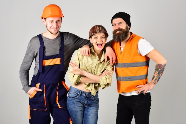 Concept de brigade de réparation. Travail d'équipe, service complet, brigade. Homme et femme avec des visages souriants en casque et combinaison, fond gris. Entreprise d'ouvriers joyeux, maçon, réparateur, plâtrier.