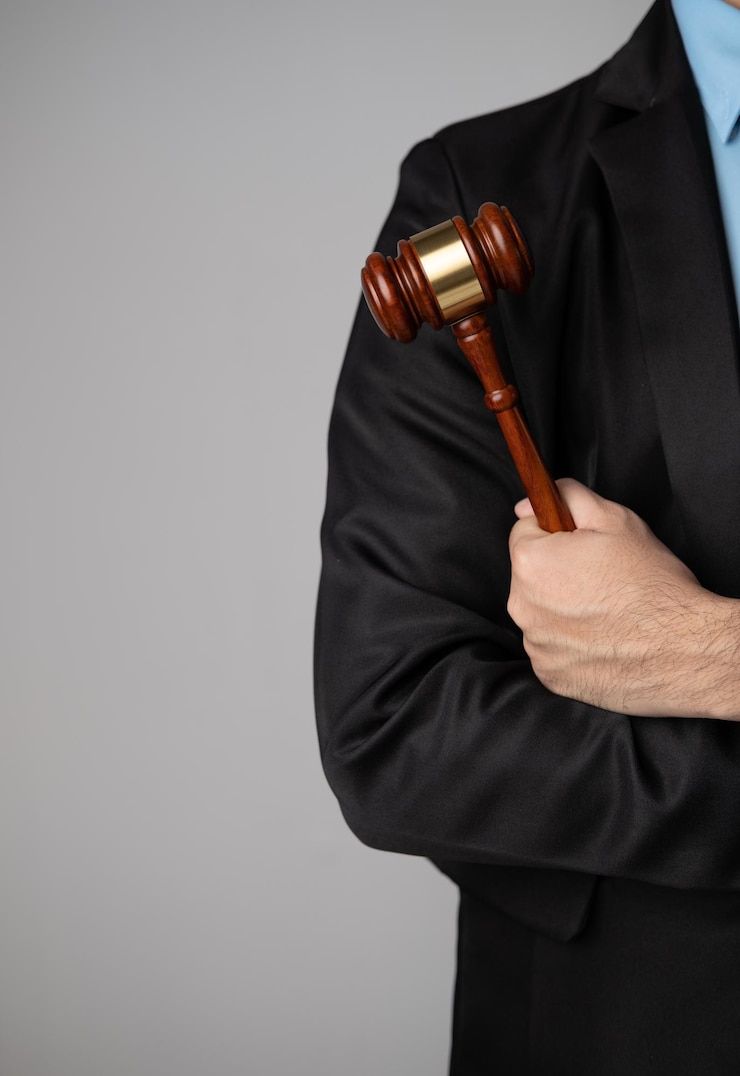 Photo concept de cabinet d'avocats vue rapprochée d'un avocat professionnel tenant le marteau des juges alors qu'il se tient contre le mur gris