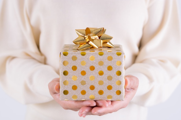 Concept de cadeaux de temps - boîte cadeau avec un arc doré dans la main fille. Concept de Noël ou de boxe. Concept d'anniversaire.