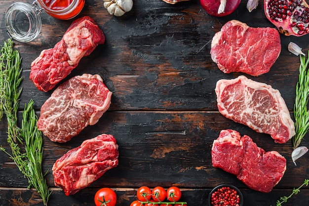 Concept de cadre de steaks de viande de boeuf, avec différentes coupes de steak sur une vieille table en bois sombre