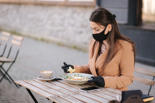 Concept de café de quarantaine sur terrasse. Jolie jeune femme assise dans un café seul.