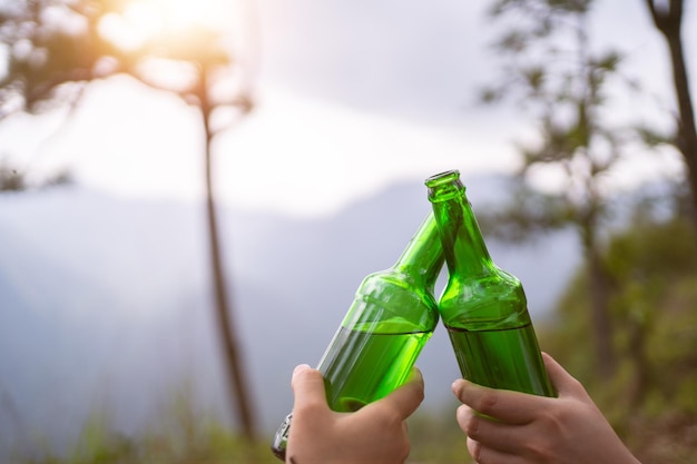 Concept de camping Cheers bouteille en verre en campant les gens ensemble sur leur site de camping à la montagne