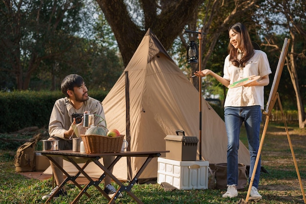 Concept de camping Jeune couple faisant une activité à l'extérieur de la tente pour peindre sur toile et prendre une photo