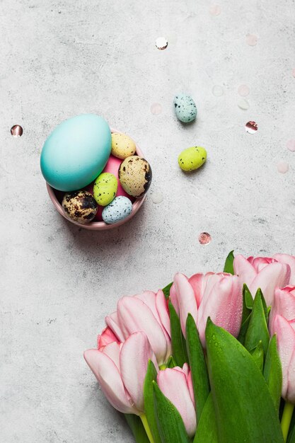 Concept de carte de voeux de Pâques bouquet de tulipes roses avec ensemble de varios pastel coloré egss sur fond de pierre grise fond de Pâques plat poser avec fond