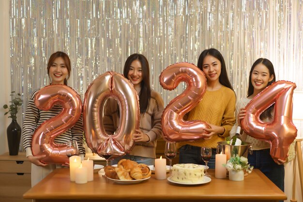 Concept de célébration d'anniversaire Les filles asiatiques tiennent le numéro 2024 d'or rose d'air de ballon dans la fête d'anniversaire