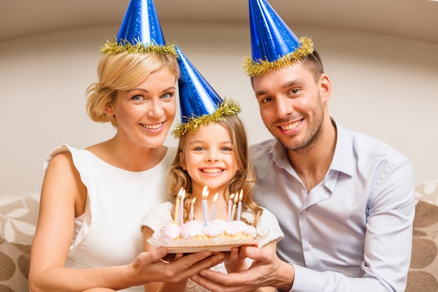 concept de célébration, de famille, de vacances et d'anniversaire - famille heureuse en chapeaux bleus avec gâteau