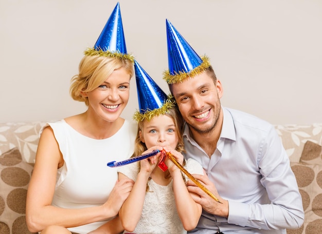 concept de célébration, de famille, de vacances et d'anniversaire - trois femmes souriantes portant des chapeaux bleus et soufflant des cornes de faveur