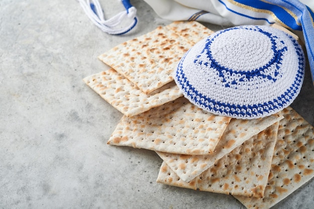 Concept de célébration de la Pâque Matzah rouge casher et noix Rituel traditionnel pain juif matzah kippa et talit sur fond de béton ancien Nourriture de la Pâque Fête juive de Pessa'h