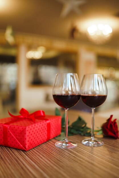 Concept de célébration de la saint-valentin Deux verres de vin boîte cadeau rouge rose rouge sur table en bois